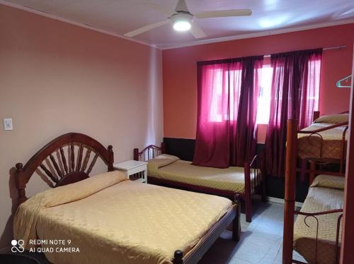 a bedroom with two beds and a window with pink curtains at Hotel Atlantic in Mar del Plata