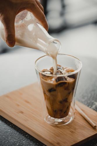 a person is pouring milk into a cup of coffee at 56 Hotel in Bangna
