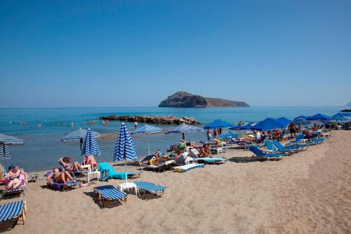 a group of people sitting on a beach with umbrellas at Ermis Suites in Platanias
