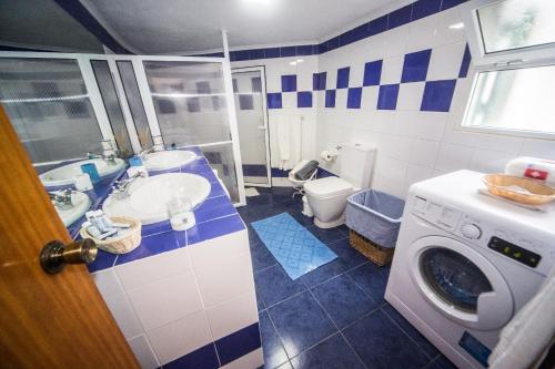 a bathroom with a toilet sink and a washing machine at Mosteiros Sea House in Mosteiros