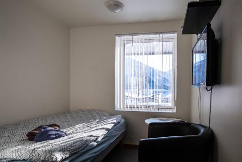 um quarto com uma cama, uma cadeira e uma janela em TorskenSenteret em Torsken