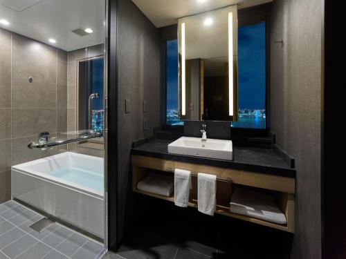 
a bathroom with a bathtub, sink and mirror at Mitsui Garden Hotel Toyosu BAYSIDE CROSS Tokyo in Tokyo
