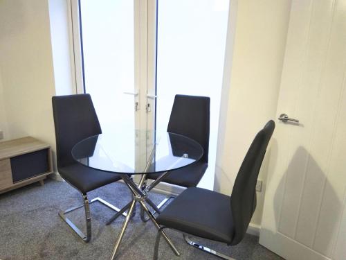 une table en verre et quatre chaises noires dans une pièce dans l'établissement Sigma Central Apartment 5, à North Shields