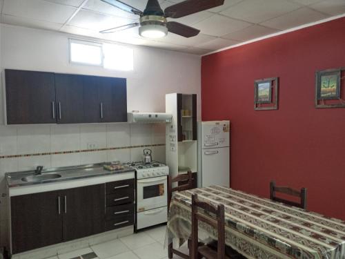 a kitchen with red walls and a kitchen with a table at Avenida Apart "Nuez de la Isla II" in Paraná