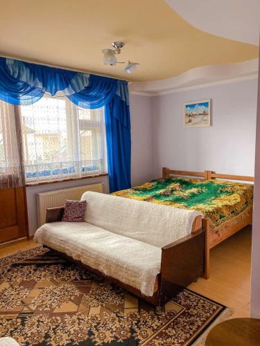 a bedroom with a couch and a bed with blue curtains at Domashnya Saduba in Mukacheve