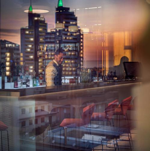 a man standing at a bar with a view of a city at J44 Lifestyle Hotel in Lido di Jesolo