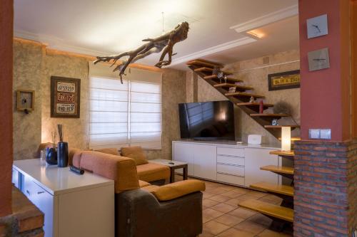 a living room with a couch and a staircase with a tv at Casa vacaciones in Castellón de la Plana