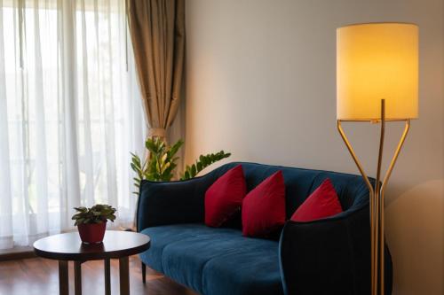 a living room with a blue couch with red pillows at Saugandhika West Gate in Wayanad
