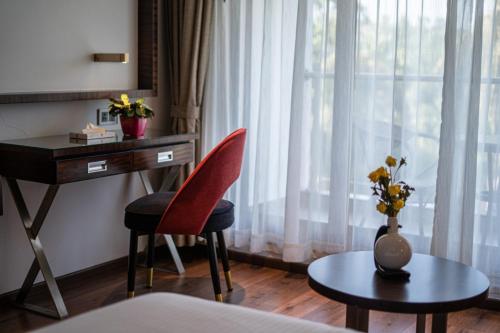 a room with a desk and a vase of flowers on a table at Saugandhika West Gate in Wayanad