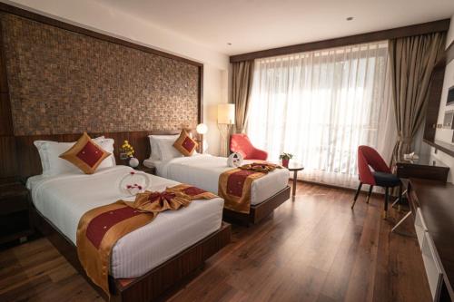 a hotel room with two beds and a window at Saugandhika West Gate in Wayanad
