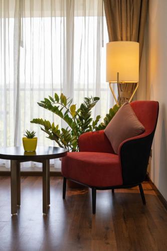 a living room with a red chair and a table at Saugandhika West Gate in Wayanad