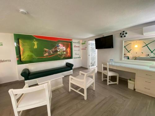 a living room with a couch and a desk with chairs at Hotel Medrano Temáticas and Business Rooms Aguascalientes in Aguascalientes