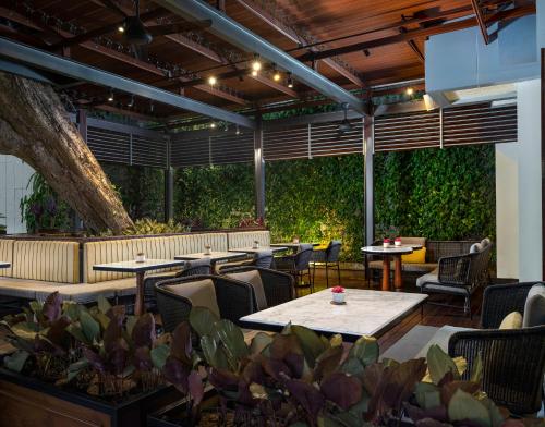 a restaurant with tables and chairs and plants at Royal Ambarrukmo Yogyakarta in Yogyakarta