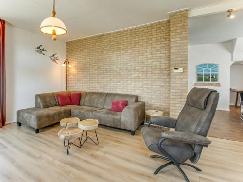 ein Wohnzimmer mit einem Sofa, Stühlen und einer Ziegelwand in der Unterkunft Classy Holiday Home in Langezwaag with Terrace in Langezwaag