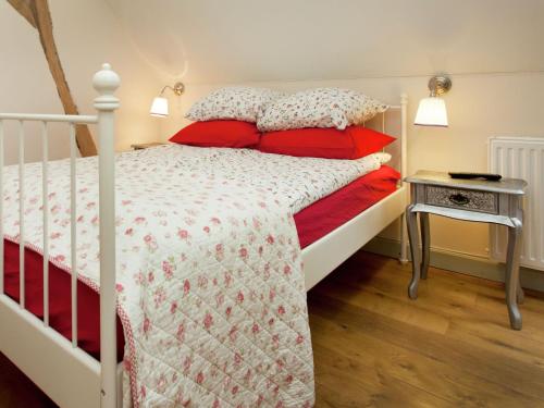 a bedroom with a white bed with red pillows and a table at Scenic Gulp Valley Stay in Slenaken