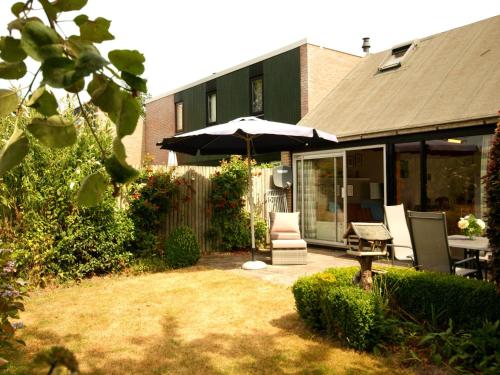 een patio met een parasol en een tafel en stoelen bij Nice holiday home in Burgh Haamstede near beach in Burgh Haamstede