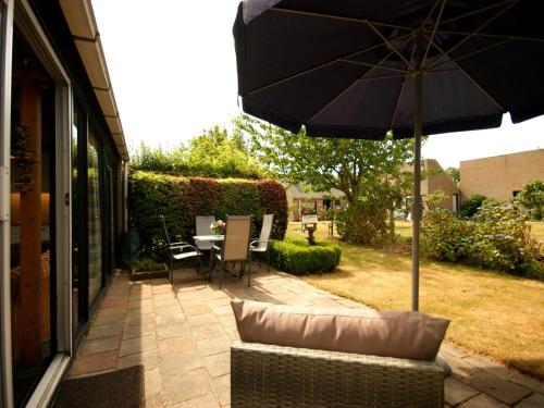 een patio met een parasol, een stoel en een tafel bij Nice holiday home in Burgh Haamstede near beach in Burgh Haamstede