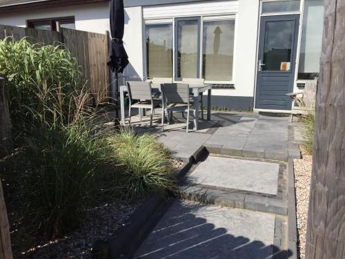 エグモント・アーン・ゼーにあるModern holiday home in Egmond aan zee near beachの家の前にパティオ(椅子、パラソル付)