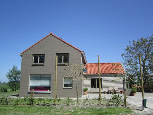 una casa con techo rojo en Holiday home in a rural location near sea, en Zuidzande