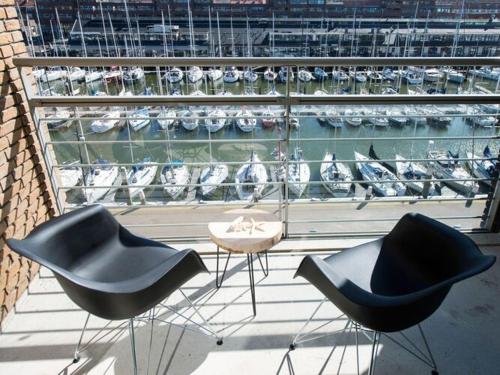 3 chaises et une table sur un balcon avec des bateaux dans l'établissement Luxury apartment near Scheveningen beach, à Scheveningen