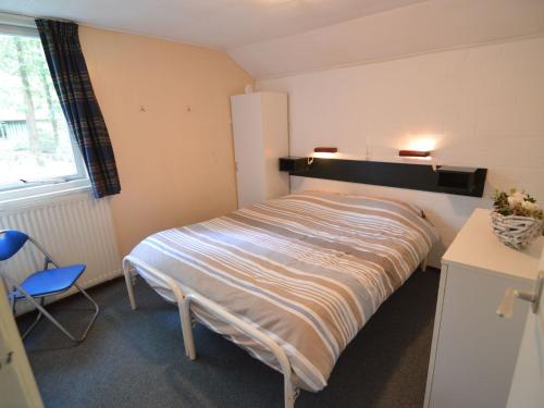 a bedroom with a bed and a chair and a window at Holiday Home in Stramproy near Nature Reserve in Stramproy