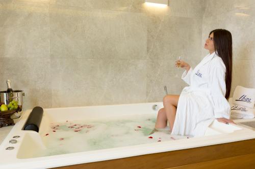 a woman sitting on the edge of a bath tub at Ibiza Hotel in Jounieh