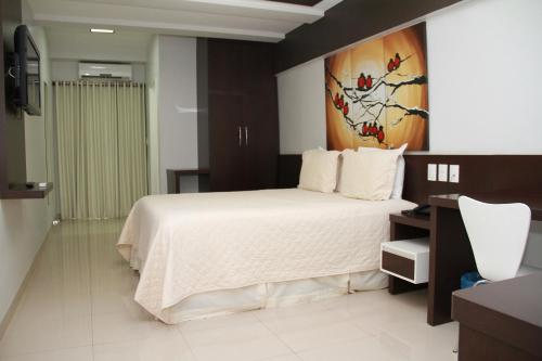a bedroom with a bed and a painting on the wall at Residence Hotel Imperatriz in Imperatriz