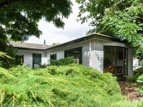 a small white house with tall grass at Tasteful chalet near Ommen for family in Stegeren