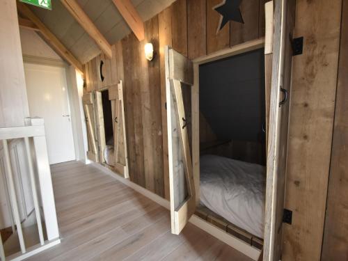 a small bedroom with a bed in a room with wooden walls at Holiday Home in Holland near Beaches in Callantsoog