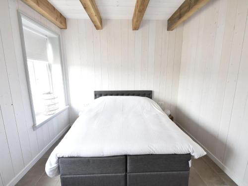 a bed in a white room with a window at Holiday Home in Holland near Beaches in Callantsoog