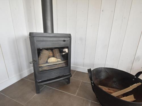a wood stove with a chair in a room at Holiday Home in Holland near Beaches in Callantsoog