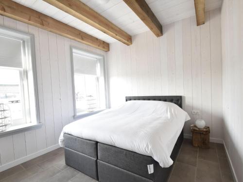 a bedroom with a bed with white sheets and two windows at Holiday Home in Holland near Beaches in Callantsoog