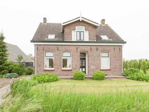 ein altes Backsteinhaus mit einem Rasenhof in der Unterkunft Lovely Cottage near Sea in Wemeldinge in Wemeldinge