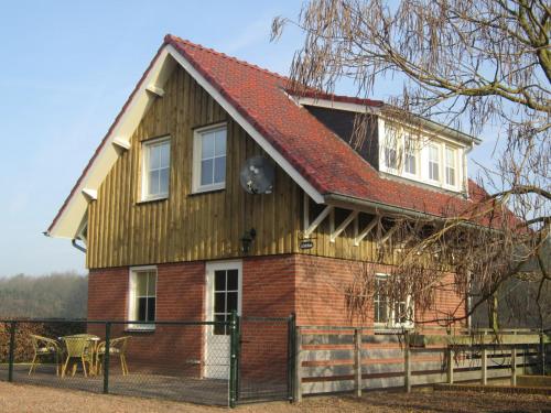 uma casa com um telhado vermelho em Rural holiday home in Well with garden em Knikkerdorp