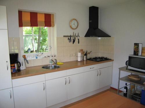 uma cozinha com armários brancos, um lavatório e uma janela em Holiday home near Grevelingen Lake em Zonnemaire