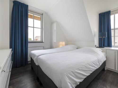 1 dormitorio con 1 cama grande y cortinas azules en Luxury villa with a sauna, at the Tjeukemeer, en Delfstrahuizen