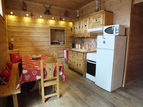 a kitchen with a table and a white refrigerator at Les Grands Champs in Attignat-Oncin