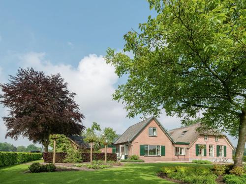 エムストにあるQuietly located holiday home in Emst with enclosed gardenの緑の芝生と木々のある家