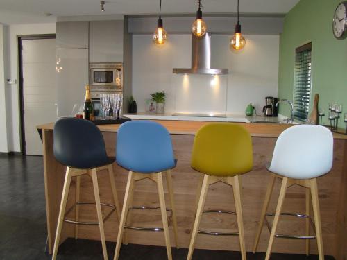 a kitchen with three chairs in front of a counter at These two holiday homes built in 2006 in Zuidzande