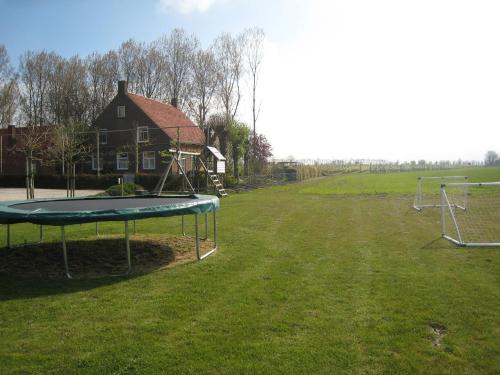 a playground with a trampoline in a field with a house at These two holiday homes built in 2006 in Zuidzande