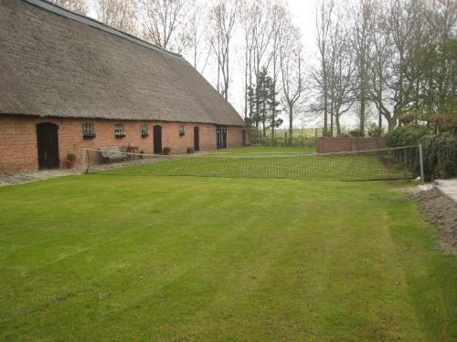 a large grass yard next to a brick barn at These two holiday homes built in 2006 in Zuidzande