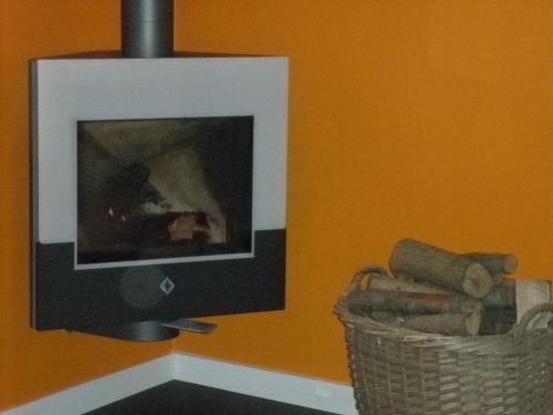 a fireplace in a room with a basket of logs at These two holiday homes built in 2006 in Zuidzande