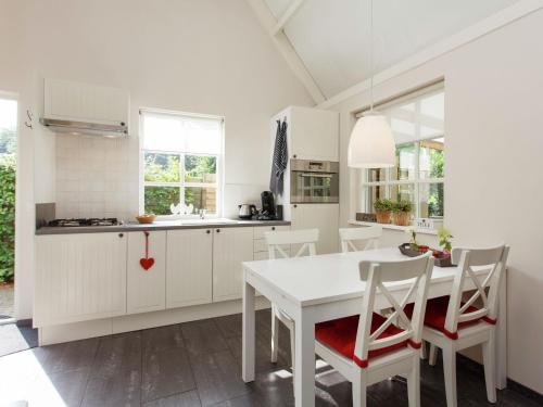 a kitchen with white cabinets and a white table and chairs at Holiday home large play sun meadow in Ravenstein