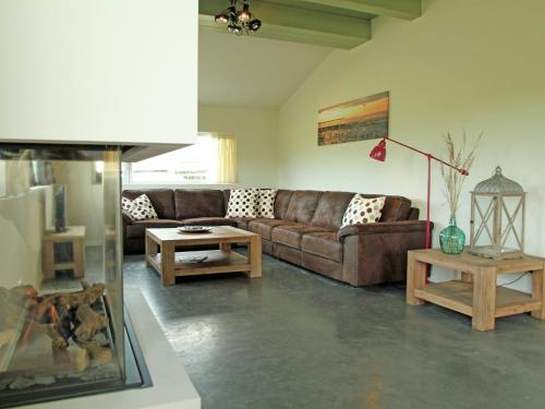 ein Wohnzimmer mit einem braunen Sofa und Tischen in der Unterkunft Quaint Villa in Tzummarum with Garden Terrace in Tzummarum