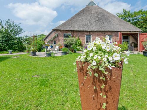 a vase of flowers in front of a house at Characteristic head neckhull farm with rowing boat in Burum
