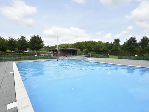 a large swimming pool with blue water at Lavish villa in Zeewolde with sauna in Zeewolde