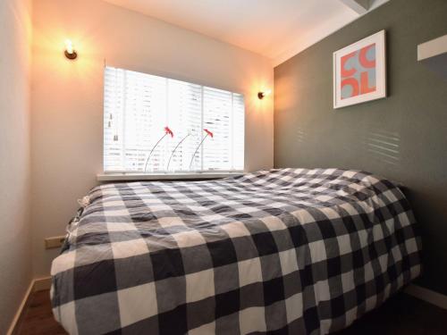 a bedroom with a checkered bed with a window at Holiday home with covered porch and sauna in Voorthuizen