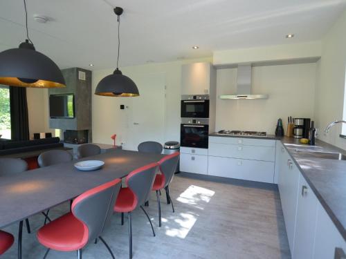 a kitchen with a table and red chairs in a room at Beautiful villa, Den Burg Texel in Westermient