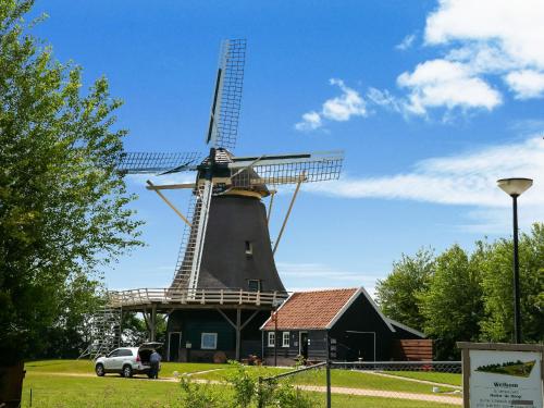 a windmill with a car parked in front of it at Holiday home in surroundings nearby the coast in Callantsoog