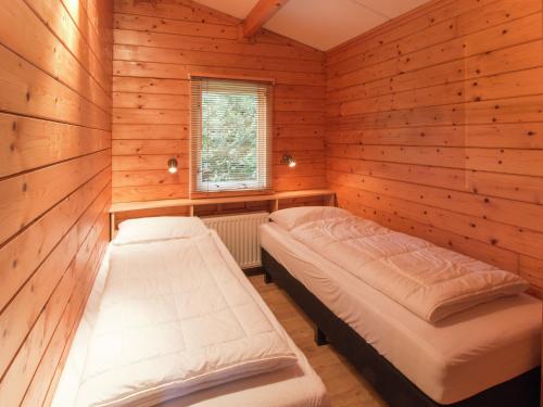 a bedroom with two beds in a wooden room at Chalet in Overijssel with Spacious Terrace in Ootmarsum